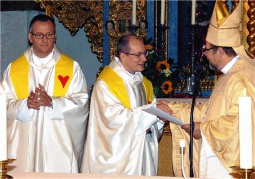 Unter den Augen von Dekan Daniel Reichel (links) übergab Weihbischof Wolfgang Bischof (rechts) die Urkunde zur Verbandserweiterung Pfarrer Andreas Przybylski. Foto th