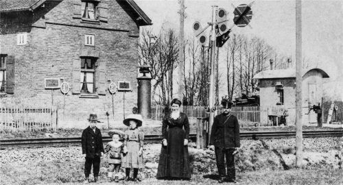 Als Joseph Eixenberger in den 1920er-Jahren den Schrankenposten 11 besuchte, um dieses Foto aufzunehmen, war dort noch alles unverfälscht bayerisch. Rechts neben dem Wärterhaus, an dem die Signalmittel vorschriftsmäßig aufgesteckt sind, steht das Läutewerk, mit dem dem Wärter die Zugmeldungen gegeben wurden, damit er rechtzeitig vor dem Herannahen eines Zuges die Schranken herunterkurbeln konnte. Die typische Wellblechbude am rechten Bildrand dient als Dienstraum, davor die Handkurbel zur Bedienung der Schranken. Das bayerische Einfahrvorsignal des nahen Bahnhofs Walpertskirchen zeigt in seiner typischen „Schmetterlings“-Bauart die Stellung „Halt erwarten“.Foto Bürger