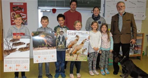 Bei der Übergabe der Kalender in Ampfing: Rektor Andre Wiesmann, Johanna Vilsmeier von der Stiftung „Treffpunkt Wildland“ und Kreisvorsitzender Dr. Erich Loserth (von links) mit Schülern der dritten Klasse der Grundschule Ampfing und Jagdhund Abu.Foto stn