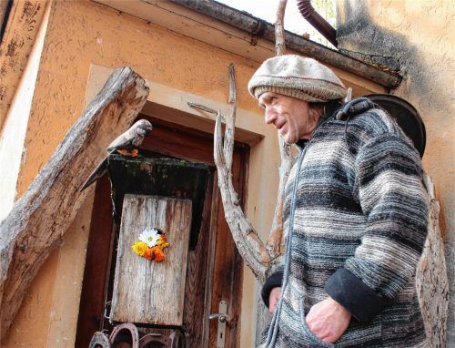 Wolfgang Wohlan bei der Arbeit an seinem jüngsten Werk: Den Ständer aus Hufeisen hat er selbst gefertigt, das Vogelhaus stammt von einem früheren Bewohner des Bahnhofes Soyen, und der Papagei kam als Schwemmholz zu ihm.Foto von Ahn