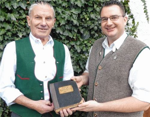 Wechsel im Amt des Schriftführers: Simon Wannersdorfer (links) übergibt Kajetan Huber junior das Schriftführerbuch, in dem die Chronik des Vereins festgehalten ist. Foto seh