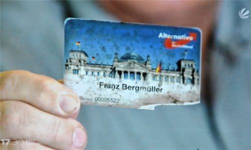 Der ist nicht mehr neu: Der Rosenheimer Landtagskandidat Franz Bergmüller hält seinen abgenutzten AfD-Mitgliedsausweis wie ein Beweisstück in die Linse einer Fernsehkamera. RE/ SAT1
