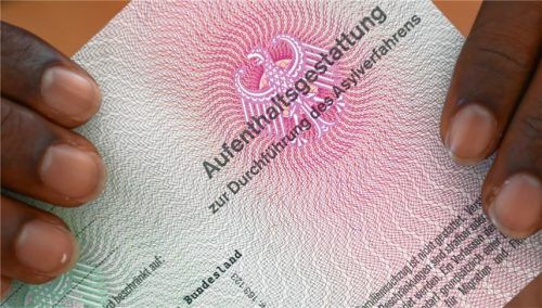 Ein Flüchtling hält seine Aufenthaltsgestattung in den Händen. An den Verwaltungsgerichten werden immer mehr Asylklagen und -eilanträge eingereicht. Foto dpa