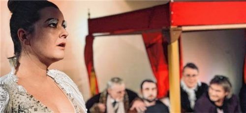 Das Szenenbild zeigt „Colomba“, gespielt von Ulrike Jörns mit dem Ensemble im Hintergrund. Foto  Petzinger