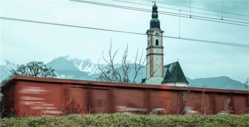 Ein Güterzug rast am Kirchturm von Flintsbach vorbei.Foto stm