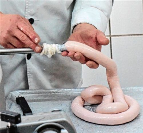 Der rosa-farbene Brei wird von den Teilnehmern in Schweinedärme gefüllt.