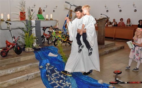 Der große starke Mann trug ein Kind nach dem anderen über den gefährlichen Fluss, samt Roller.RE