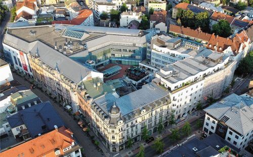 Die Terrasse als Herz des Gebäudekomplexes (Innenhof in der Bildmitte) ist fertig, rechts im Bild zeigt sich die Fassade des neuen Gillitzers noch zum Teil hinter Planen verdeckt. Sie wird nicht länger mehrfarbig sein, sondern in einem einheitlichen Sandton gestrichen. Außerdem erhält das Gebäude eine neue Licht- und Werbeanlage. Foto Ziegler
