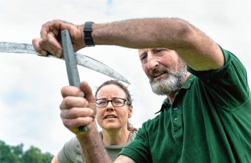 Volle Konzentration: Ursula Bernritter prägt sich jeden Handgriff von Sepp Mayer ein, denn eine scharfe Schneide ist das A und O beim Mähen mit der Sense. Fotos Thomae