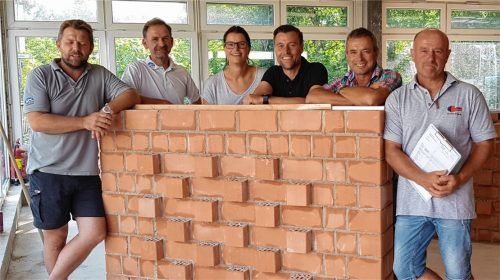 Angela Kneissl umringt vom Prüfungsausschuss nach Abschluss der Gesellenprüfung 2018 nach der Bewertung der Gesellenstücke – hier ein Mauerwerk. Foto re