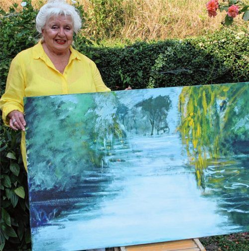 Angela Rittershaus mit einem ihrer Gemälde, das eine von Monet inspirierte Teichlandschaft zeigt. Foto Mergenthal