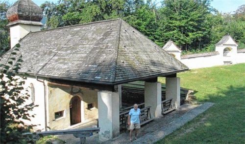 Die Wallfahrtskirche St. Magdalena mit Kreuzwegstationen im Hintergrund. Rechts die beiden Restauratorinnen Laura Lon und Veronika Disl mit Kirchenpfleger Heinz Steiner.Fotos re