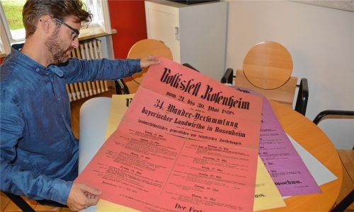 Abwechslungsreich bunt: Stadtheimatpfleger Karl Mair zeigt die Original-Plakate, die für das Volksfest 1898 in verschiedenen Farben gedruckt worden waren. Foto Weinzierl