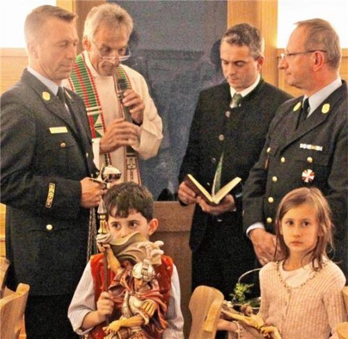 Bei der Segnung des neuen Wachstüberls in der Rosenheimer Hauptfeuerwache: (stehend von links) Stadtbrandinspektor Mario Zimmermann, Pfarrer Andreas Maria Zach, Stefan Reimann, der Stifter der Sankt-Florian-Figur, Stadtbrandrat Hans Meyrl sowie (sitzend von links) Simon Reimann und Katharina Meyrl mit der Florian-Figur und dem Kreuz.Foto  Binder