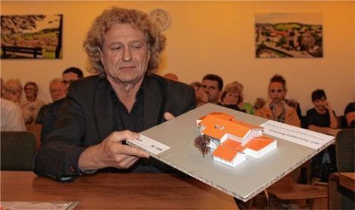 Planer Johann Schmuck mit der Variante, die auch dem Gemeinderat am besten taugt. Das Pultdach als Aufstockung für den Kindergarten, das in einer früheren Sitzung vorgestellt wurde, kam nicht so gut an. Jetzt wird es ein Satteldach. Die Überdachung zwischen Bewegungsraum und Kita wird auch gemacht.Foto kla