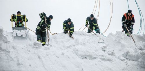 Und runter damit: Einsatzkräfte befreien hier ein Dach in Siegsdorf von der gewaltigen Schneelast. Tausende Helfer schaufeln im Januar Tag und Nacht. Foto Lamminger