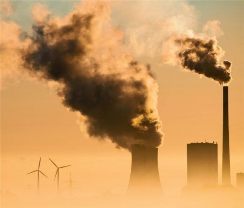 Bezeichnendes Bild für den Klimawandel? Qualmender Kamin eines Kohlekraftwerks neben Windrädern. Foto dpa