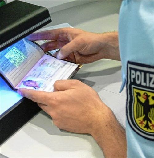 Ein Polizeibeamter prüft einen Reisepass auf seine Echtheit.
