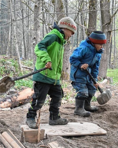 Im Sandkasten: Kinder spielen mit ihren Schaufeln im Sand – auch das ist im Waldkindergarten möglich.
