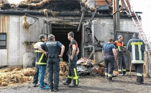 Hier brach das Feuer aus: Kreisbrandrat Richard Schrank, Kripo-Ermittler und Feuerwehrler (von links) vor dem Pferdestall auf Gut Heiming. Ein glimmender Zigarettenstummel dürfte den Großbrand ausgelöst haben. Foto simeth