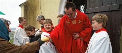 Pfarrvikar Emmeran Hilger verteilte eine „historische Brotspende an die Armen“, so wie es einst Johann Georg Riedl festgelegt hatte. Foto  Meling