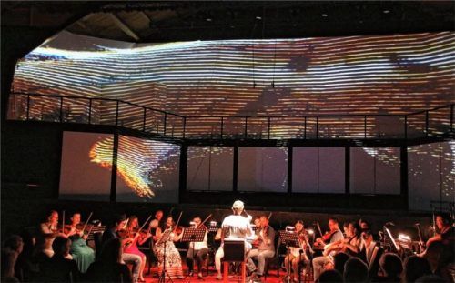 Die Georgian Sinfonietta und Solo-Instrumentalisten agierten unter der Leitung von Cornelia von Kerssenbrock vom ersten Moment an in engstem Austausch. Die dunkle Bühne war dabei Projektionsfläche für die Visualisierungen von Anna Zozulya. Foto Benekam