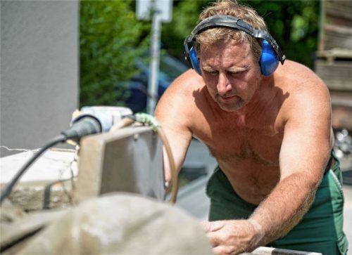 Ein Handwerker schneidet auf einer Baustelle einen Pflasterstein zu. Laut Meteorologen ist in den kommenden Tagen mit Temperaturen über 30 Grad zu rechnen.Foto  dpa