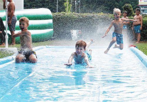 Anlauf und dann möglichst weit kommen auf der Schlitterbahn. Je mehr das Wasser dabei spritzt, um so mehr Spaß macht es den Kindern.