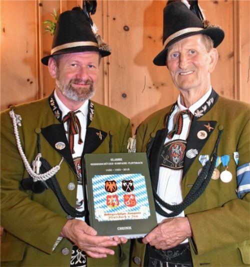 Ehrenhauptmann Max Dirl (rechts) übergibt die von ihm verfasste Chronik „65 Jahre Gebirgsschützen Kompanie Flintsbach“ an Hauptmann Walter Wons.Foto Johann Weiß