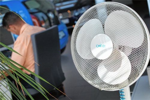 Ein Ventilator kühlt den Arbeitsplatz eines Autohaus-Mitarbeiters. Da Klimaanlagen in der Region derzeit so gut wie ausverkauft sind, fragen Verbraucher nun verstärkt nach Alternativen. Fotos dpa, re (2)
