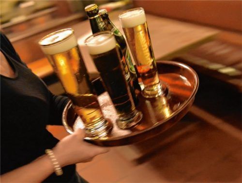 Eine Bedienung trägt in einem Lokal ein Tablett mit Getränken: Das Gastgewerbe leidet unter Personalmangel, mehr als die Hälfte der Beschäftigten kommt laut der Bundesagentur für Arbeit aus dem Ausland. Fotos dpa/re (2)