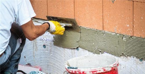 Handwerker sind gefragt: Ein Maurer trägt auf einer Baustelle Klebemörtel auf eine Wand auf.Foto picture alliance/Lino Mirgeler/dpa