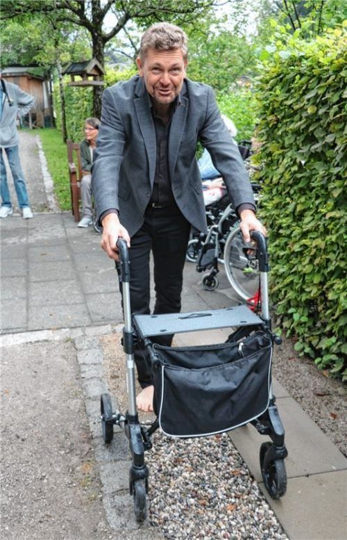 Rainer Küblbeck von der Baufirma erprobt den „Barfuß-Sinnespfad“ auf seine Tauglichkeit mit dem Rollator.