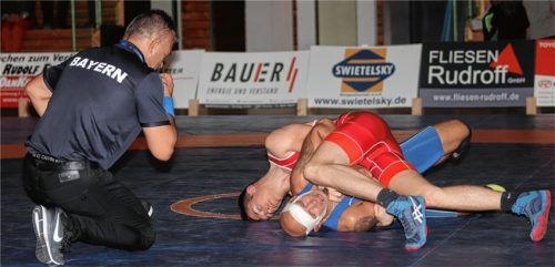 Überzeugte: Traunsteins Ben Wittenzellner (rotes Trikot) gewann gegen den ehemaligen deutschen Vizemeister Roland Rehm. Mattenleiter Petar Stefanov erklärte den Schultersieg. Foto wittenzellner