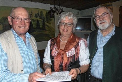 Im Jahr 2014 gab er den Startschuss für die Wirtshaussingen in Kraiburg. Jetzt gibt Hermann Brunner (links) die Notenblätter weiter an Christa Fuchs. Kreisheimatpfleger Dr. Reinhard Baumgartner wird auch sie bei den Veranstaltungen unterstützen.Foto  Fill