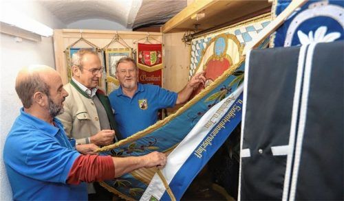 Im neuen Lagerraum: Erwin Schnetzer (von links), Bürgermeister Alois Salzeder und Vorsitzender Siegfried Oswald vor dem eigens angefertigten Fahnenschrank, in dem alte und neue Fahnen und Bänder des Vereins sauber sortiert eingelagert sind.Foto Höpfinger