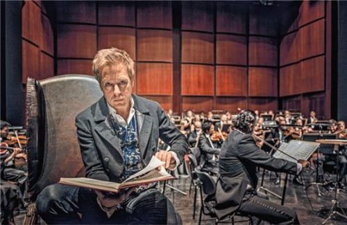 Max Müller bei einer Lesung und den Münchner Symphoniker im Hintergrund. Foto Felbert