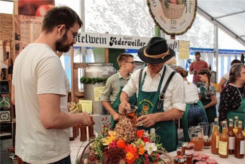 Sepp Millauer (rechts), Vorsitzender des Obst- und Gartenbauvereins Au-Dettendorf, erklärt an der historischen Apfelpresse die Vorzüge frischen Apfelmosts.