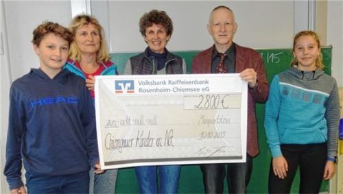Symbolische Scheckübergabe: Maxi Erhardt (links) und Mona Aumann (rechts) an Angelika Drost (Mitte), Leiterin der Aktion Chiemgauer Kinder in Not, und Schulleiter Christian Thoma (Zweiter von rechts).Foto re