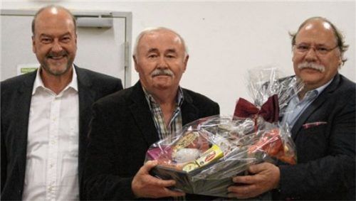 Mit einem Geschenkkorb bedanken sich der Zweite Vorsitzende des ESV Rosenheim, Dr. Wolfgang Bergmüller (links), und der Vorsitzende Horst Spensberger (rechts) bei Rudi Purainer. Er gehört dem Verein seit 70 Jahren an.Foto Re