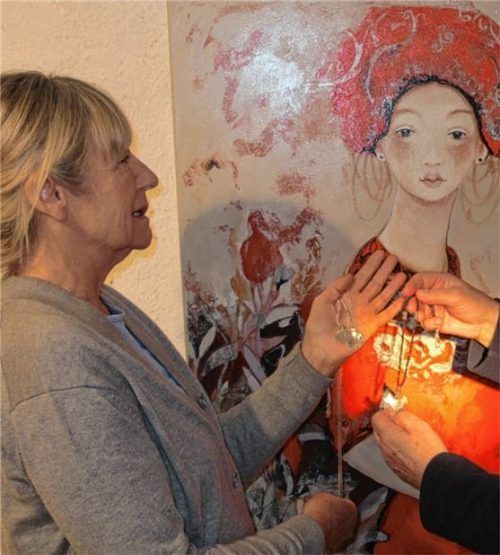 Olivia Weinert (links) und einige ihrer Schmuckkreationen vor einem Gemälde von Aldona Sassek, die derzeit gerne Weinerts Enkelin in den Mittelpunkt ihrer Gemälde stellt. Foto  Heuser