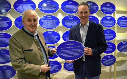 Breitbrunns Dorfarchivar Franz Burghardt (links) übergibt ein „Schulhaus“-Schild an Bürgermeister Anton Baumgartner im Rahmen der Vernissage im Haus des Gastes. Foto Wastl