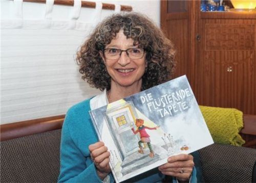 Brigitte Largeteau zeigt das Buchcover, mit dem ihre Geschichte „Die flüsternde Tapete“ erscheint. Foto  Bartschies
