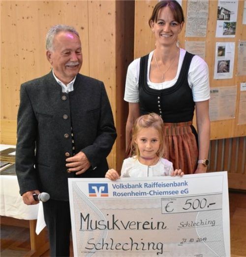 Übergabe der Spende: Der Vorsitzende des Elektrizitätswerkes Schleching, Jakob Riedelsperger (links), übergab mit seiner Enkelin einen symbolischen Spendenscheck in Höhe von 500 Euro an Barbara Pletschacher, Vorsitzende der Musikkapelle.Foto wunderlich