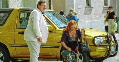 Ein Bild aus den Anfangstagen der Rosenheim-Cops im Jahr 2000 (ausgestrahlt 2002): Der noch junge Joseph Hannesschläger bei Dreharbeiten in Rosenheim – im weißen Anzug und bei bester Laune, umgeben von einigen Komparsen, die schon zu damaliger Zeit das Theater Rosenheim stellte.