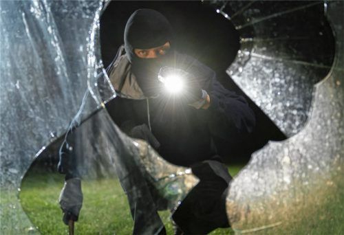Ein fiktiver Einbrecher blickt an einem Haus durch eine eingeschlagene Fensterscheibe. In Pang sind bisher unbekannte Täter in mindestens vier Wohnhäuser eingedrungen.Foto dpa