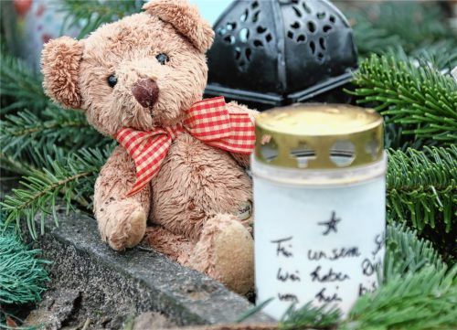 Der Verlust eines Kindes ist für Eltern eine dramatische Situation. Mit einer Kerze und einem Teddybär gedenken Eltern ihres verstorbenen Kindes an einem Grab. Foto  Stephanie Pilick/DPA
