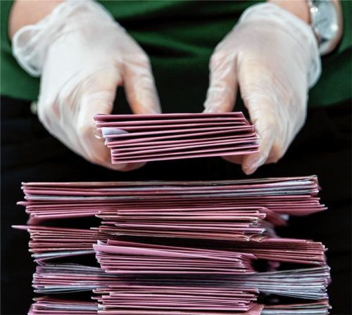 Ein Wahlhelfer mit Schutzhandschuhen stapelt Wahlbriefe. Trotz der widrigen Umstände durch die Corona-Krise war die Wahlbeteiligung im Raum Rosenheim deutlich höher als 2014. Foto dpa