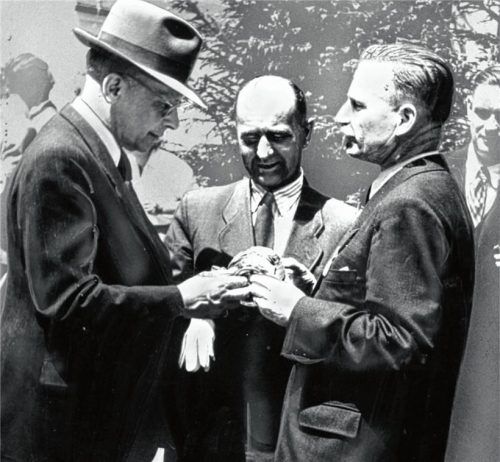 Ein Glasgeschenk überreichte Bürgermeister Hubert Rösler (rechts) bei der Gemeindegründungsfeier im Mai 1950 an den Staatssekretär für das Flüchtlingswesen, Wolfgang Jaenicke (links), und Wirtschaftsminister Hanns Seidel.