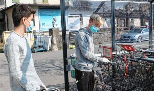 Zum Eigenschutz und Schutz der anderen vor Corona tragen diese Kunden Schutzmasken und desinfizieren den Griff ihres Einkaufswagens, bevor sie den Frasdorfer Edeka-Markt betreten.Foto rehberg